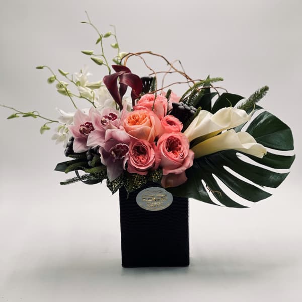 Bouquet of pink roses, orchids, and white calla lilies in a black box
