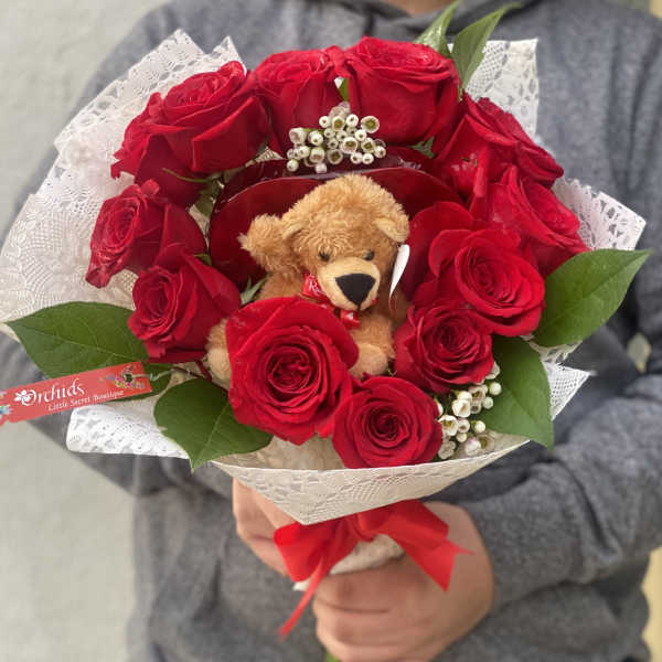 Bouquet of red roses with a teddy bear and white lace wrap