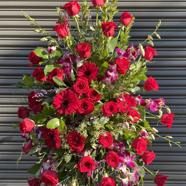 Tall standing spray of red roses and pink orchids on an easel