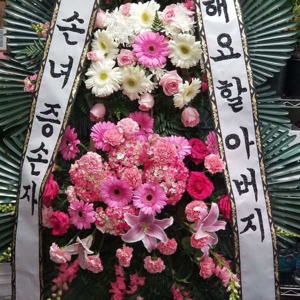 Standing funeral wreath with pink and white flowers and Korean condolence ribbons