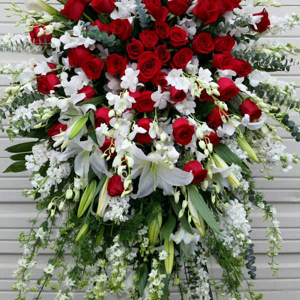 Large standing floral spray with red roses, white lilies, and white orchids