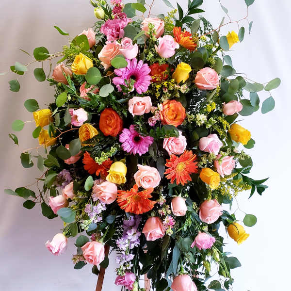 Large mixed flower arrangement on an easel with pink, yellow, and orange blooms