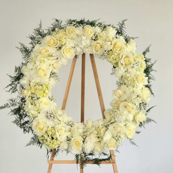 White rose and hydrangea wreath on a wooden easel