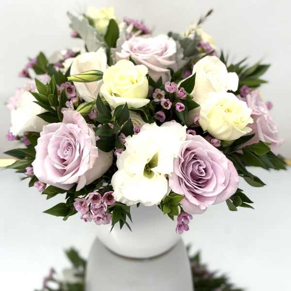 Pastel roses and white blooms arranged in a white vase