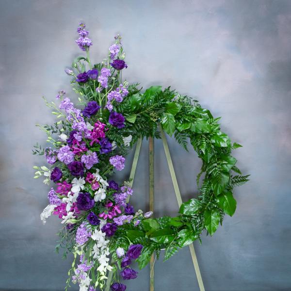 Purple and white floral wreath on a stand