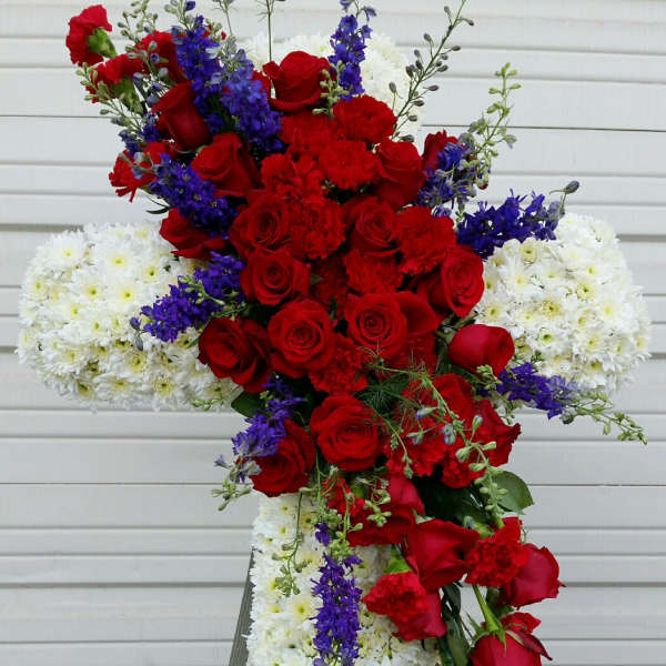 Standing floral cross with red roses, white chrysanthemums, and purple accents
