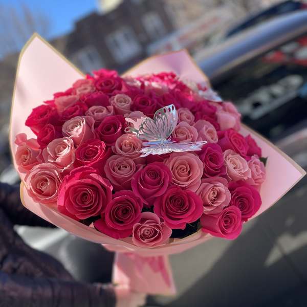 Bouquet of pink and hot pink roses with a butterfly pick