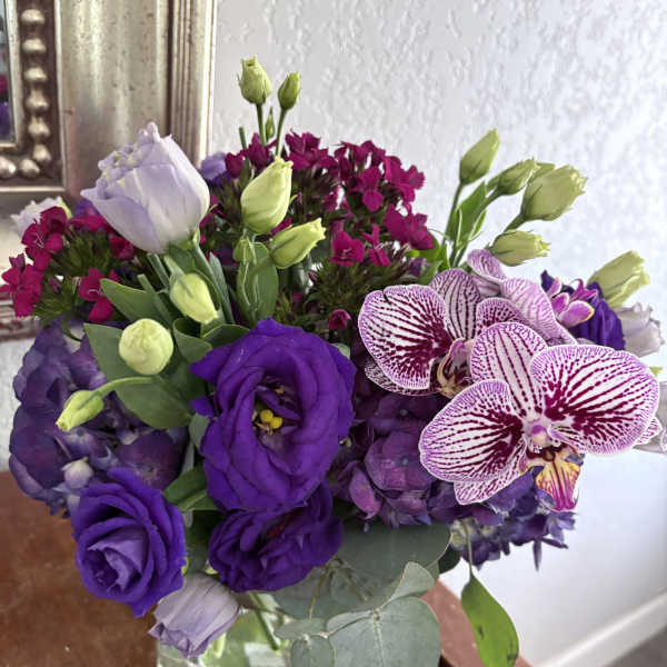 Purple bouquet with orchids, lisianthus, hydrangea, and a glass vase