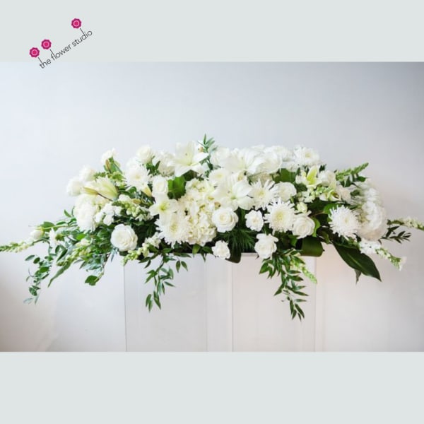 White floral casket spray with cascading greenery
