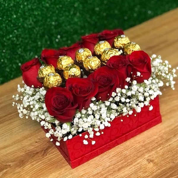 Red roses and gold-wrapped chocolates in a red box with white baby's breath