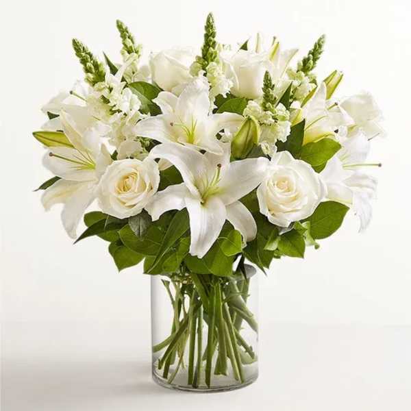 White lilies and roses arranged in a clear glass vase