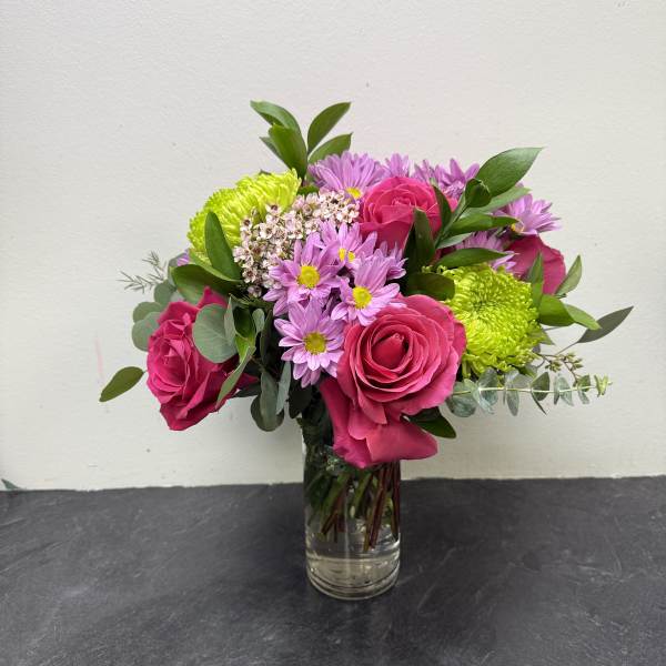 Bouquet of pink roses and purple daisies in a clear glass vase