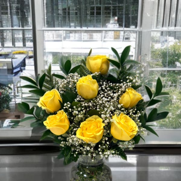 Yellow roses arranged in a clear glass vase with white filler flowers