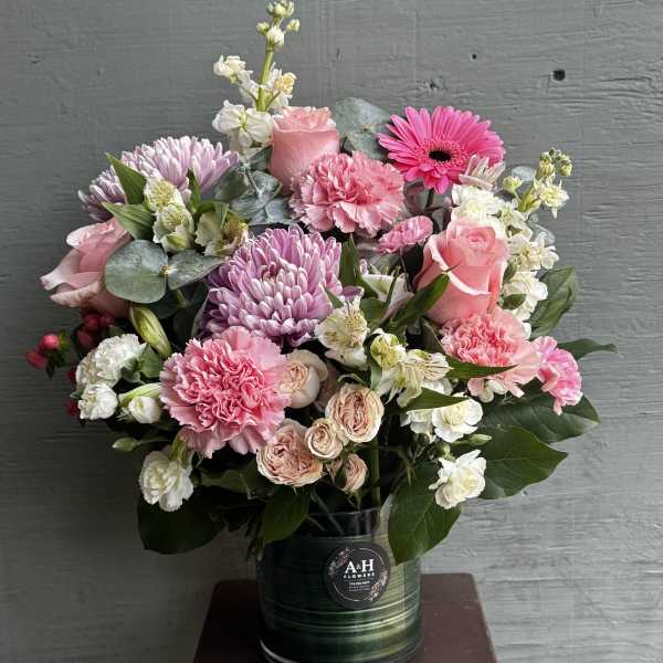 Pink and white mixed flower arrangement in a dark vase