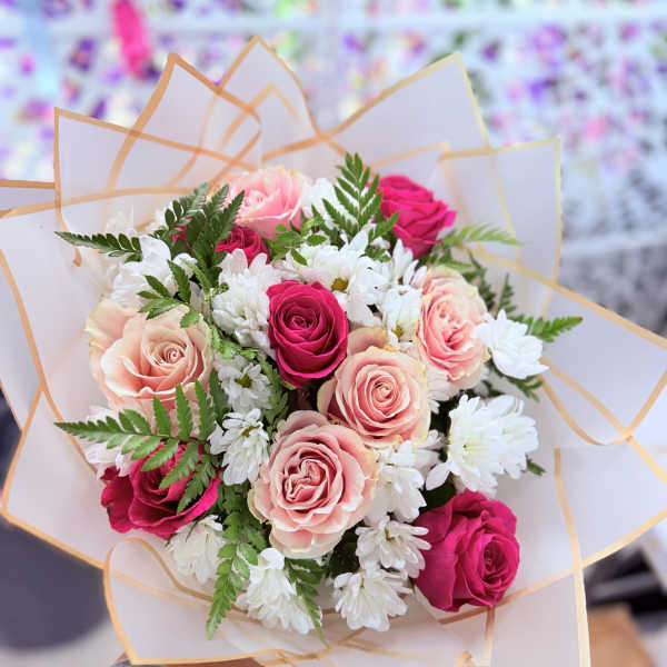 Bouquet of pink and white roses with white daisies in pale wrapping