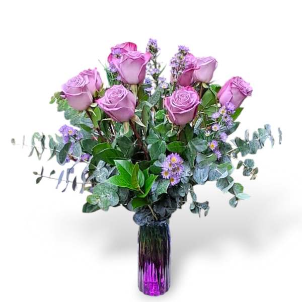 Lavender roses in a purple glass vase with small purple filler flowers
