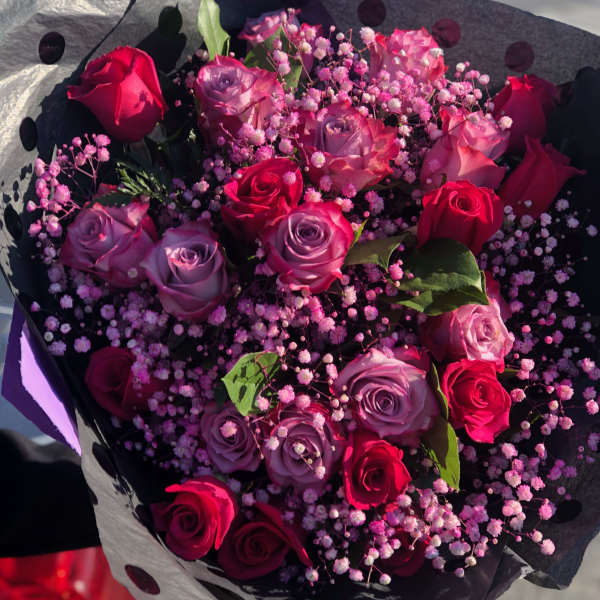 Bouquet of red and lavender roses with pink baby's breath in black polka-dot wrap