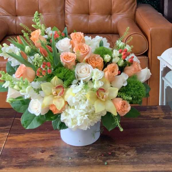 Peach and white floral arrangement in a white vase on a table