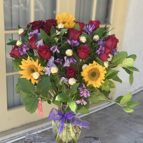Bouquet of red roses and yellow sunflowers in a glass vase