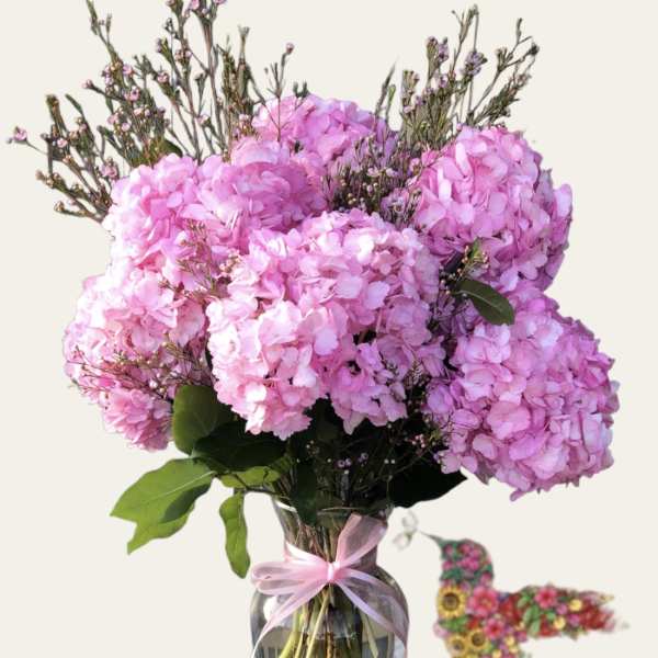 Pink hydrangea bouquet in a glass vase with a ribbon