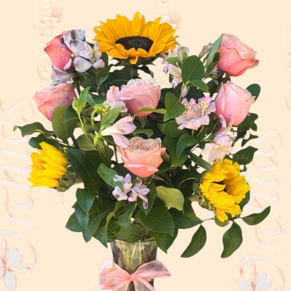 Pink roses and yellow sunflowers in a glass vase with a ribbon