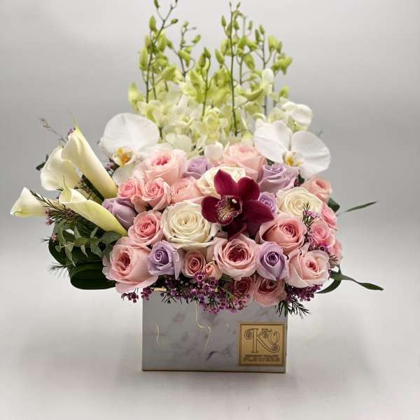 Pink and lavender roses with white orchids in a square box