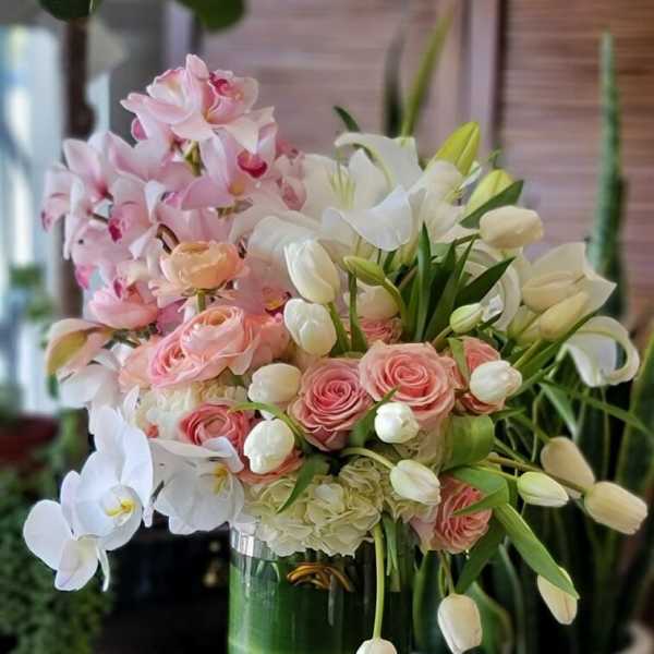 Pink and white floral arrangement in a tall glass vase