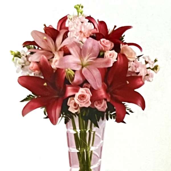 Pink and red floral bouquet in a tall pink glass vase