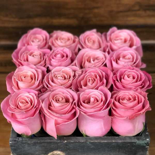Pink roses arranged in a rustic wooden box tied with twine