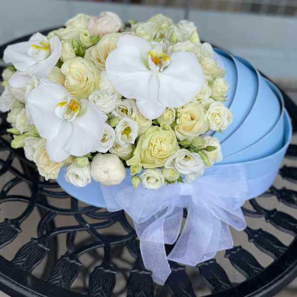 White rose and orchid bouquet in a light blue hatbox with a sheer ribbon