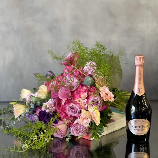 Pink and lavender flower arrangement beside a champagne bottle