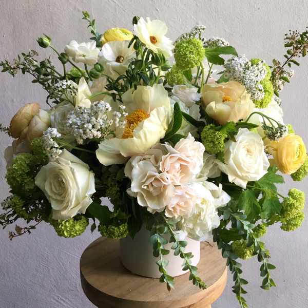 Large white and pale yellow flower arrangement in a white vase