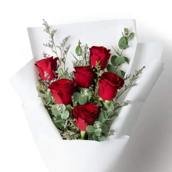 Bouquet of red roses wrapped in white paper with a red ribbon