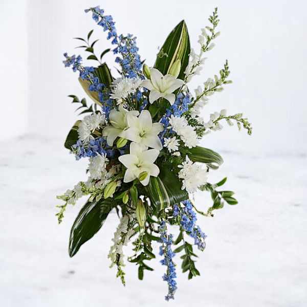 White lilies with blue and white flowers in a cascading arrangement
