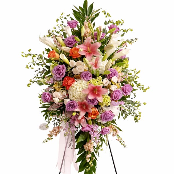 Standing floral spray with pink lilies, purple roses, and white blooms