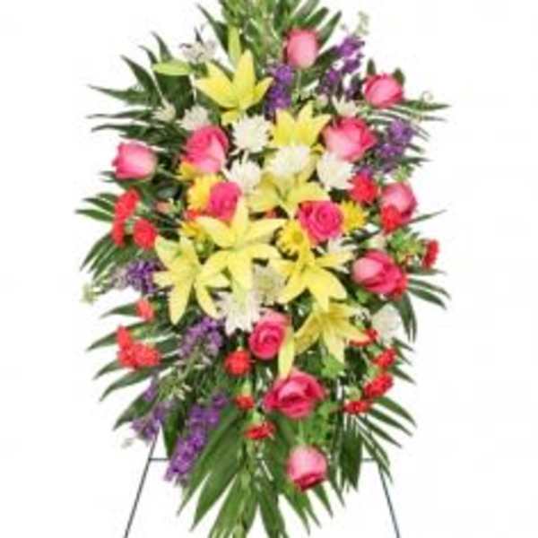 Standing floral spray with pink roses, yellow lilies, and purple accents