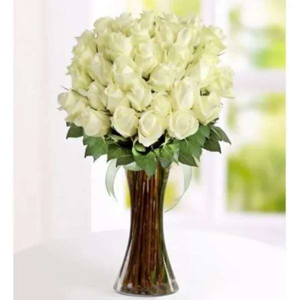 Tall clear glass vase filled with a large bouquet of white roses