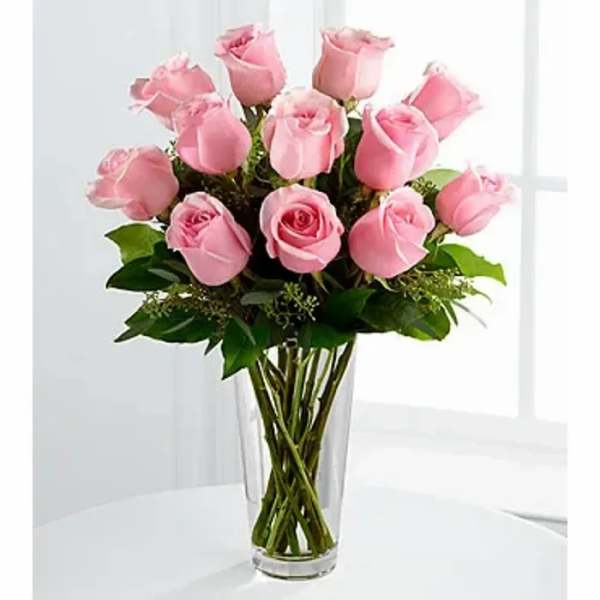 Tall clear glass vase filled with a dozen light pink roses