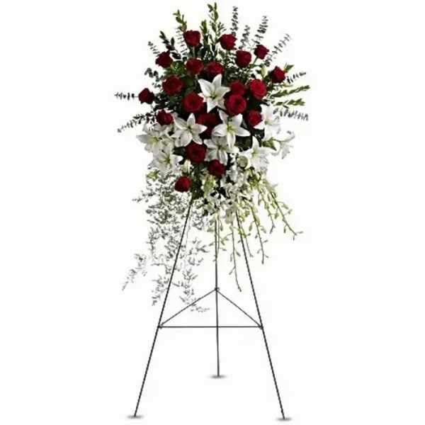 Standing floral spray with red roses and white lilies on an easel
