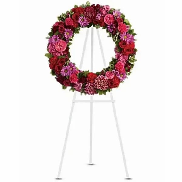 Circular floral wreath on a white easel with pink and red flowers
