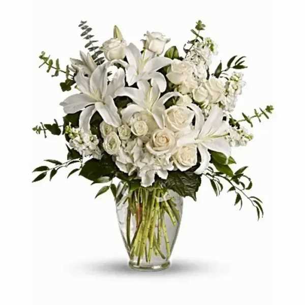 White lilies and roses arranged in a clear glass vase