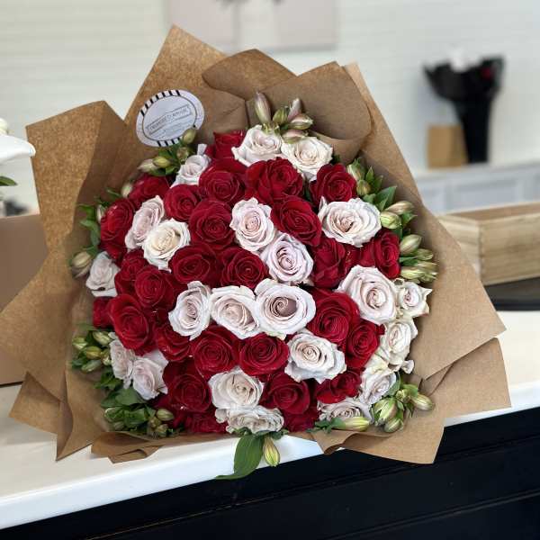 Large bouquet of red and white roses wrapped in brown paper