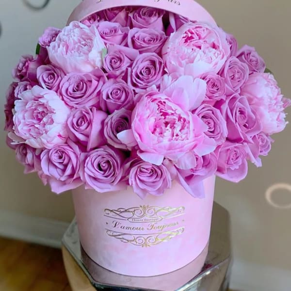 Pink roses and peonies arranged in a round pink hat box