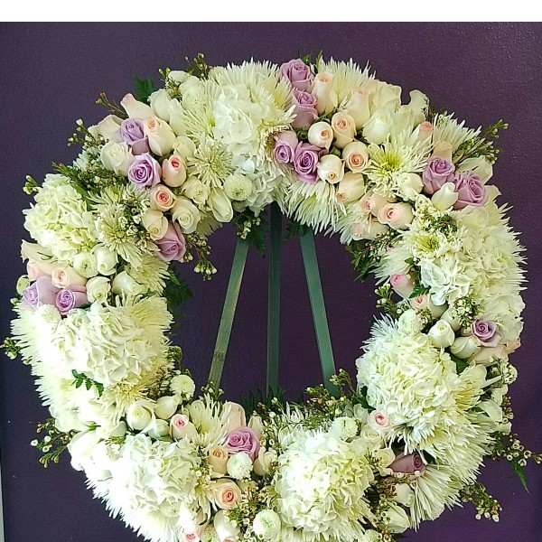 Large floral wreath of white and lavender blooms on a stand