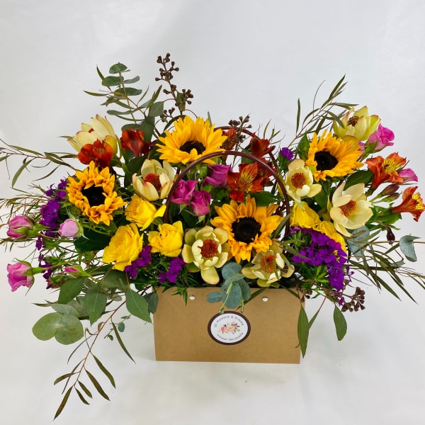 Mixed bouquet with sunflowers, roses, and purple blooms in a kraft box