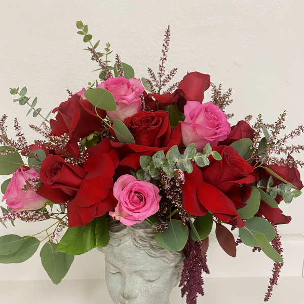 Arrangement of red and pink roses in a gray head-shaped vase