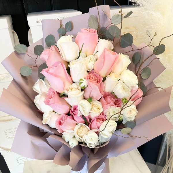 Bouquet of pink and white roses wrapped in mauve paper