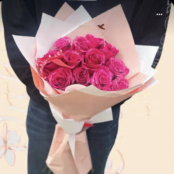 Bouquet of bright pink roses wrapped in pale paper