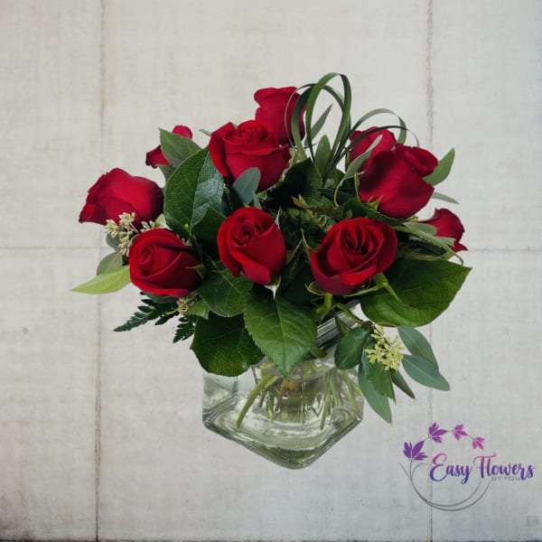 Red roses arranged in a clear square glass vase
