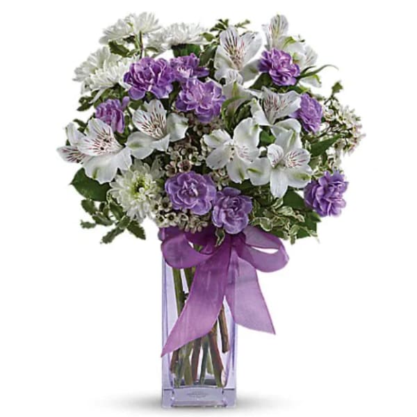 Purple and white bouquet in a clear glass vase with a ribbon